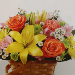 Mixed bouquet in a woven basket with orange roses and yellow lilies