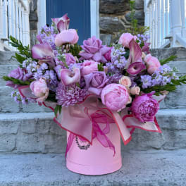 Pink and lavender bouquet in a pink hatbox with ribbon