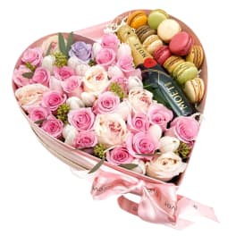 Heart-shaped box of pink roses and macarons with a ribbon bow