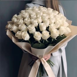 Large bouquet of white roses wrapped in beige paper with a ribbon