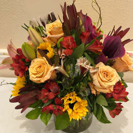 Mixed bouquet of roses, lilies, and sunflowers in a glass vase