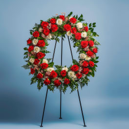 Circular standing wreath of red roses and white flowers on an easel