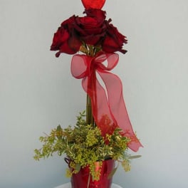 Tall red rose arrangement in a red vase with a sheer ribbon