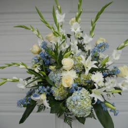 Tall white and blue floral arrangement with roses and lilies