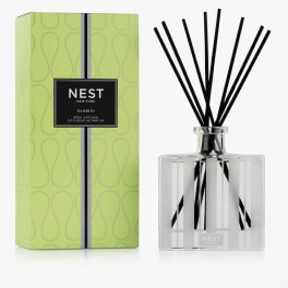 Reed diffuser in a clear glass bottle with black reeds and a green box