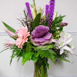 Mixed bouquet with purple, pink, and white flowers in a glass vase