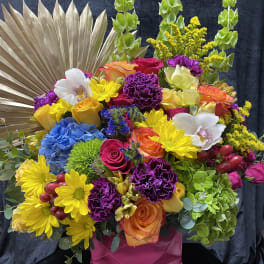Colorful mixed bouquet in a pink vase with a gold fan backdrop