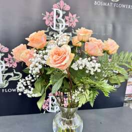 Peach roses with baby's breath in a clear glass vase
