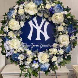 Round floral wreath with white roses and blue flowers around a New York Yankees sign