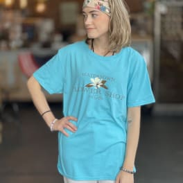 Woman wearing a turquoise flower shop T-shirt and floral headband