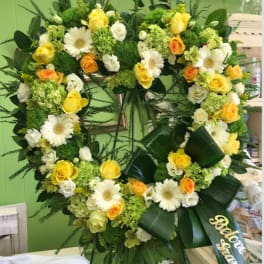 Large heart-shaped floral wreath with yellow and white flowers on an easel