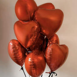Cluster of red heart-shaped balloons tied with black ribbons