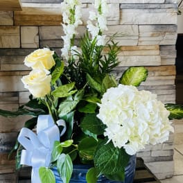 White roses and hydrangea in a blue vase with a pale ribbon