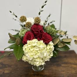 Red roses and white hydrangea in a glass vase with gold accents