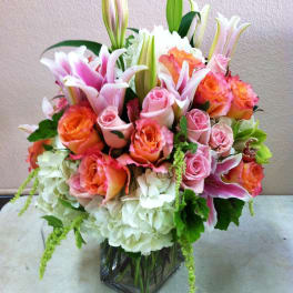 Bouquet of pink and orange roses with lilies in a glass vase