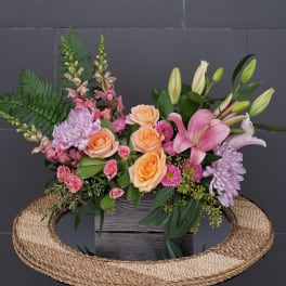 Mixed bouquet with peach roses, pink lilies, and lavender chrysanthemums in a wooden box