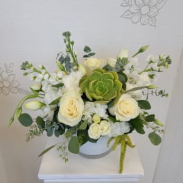 White rose arrangement with a green succulent in a white vase