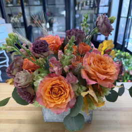 Orange and purple roses arranged in a square container