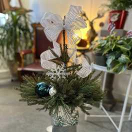 Small holiday evergreen arrangement with a white ribbon bow and ornaments