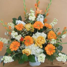 Orange gerbera daisies and yellow roses in a white vase