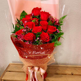 Bouquet of red roses wrapped in pink and red paper with a ribbon