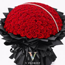 Large dome bouquet of red roses with a pearl strand and black wrapping paper.