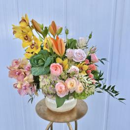 Mixed bouquet in a ribbed white vase with yellow orchids and pink roses