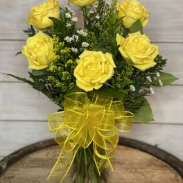 Bouquet of yellow roses in a glass vase with a yellow ribbon