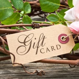 Gift card tag tied to a rose stem with pink rose petals nearby