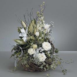 White floral arrangement in a wicker basket with ribbon