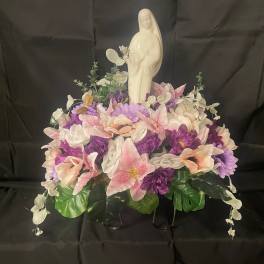 White statue surrounded by pink, purple, and white flowers