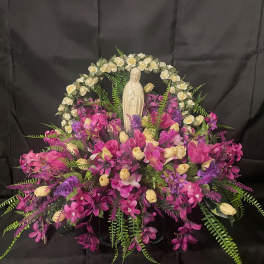 Pink and purple floral arrangement with a small religious statue