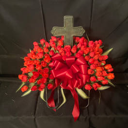 Red rose arrangement with a large ribbon and cross backdrop
