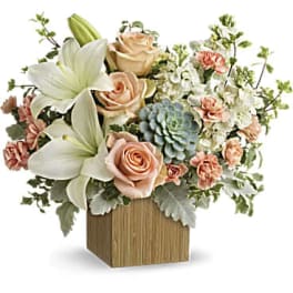 Arrangement of lilies, roses, carnations, and succulents in a wooden cube vase