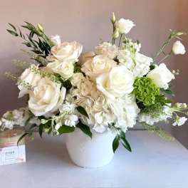White roses and hydrangeas arranged in a white vase