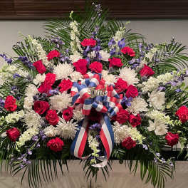 Large red, white, and purple floral spray with a patriotic ribbon