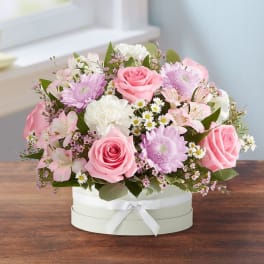 Pink and white mixed flower arrangement in a round box with ribbon