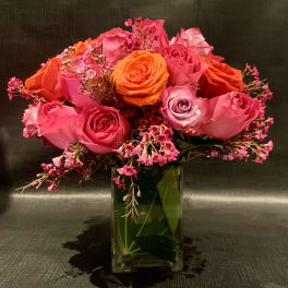 Pink and orange roses arranged in a clear glass vase