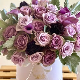 Lavender roses and dark calla lilies in a white hat box