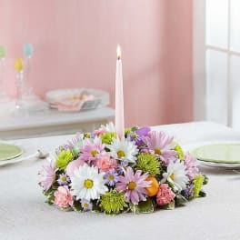 Low floral centerpiece with a pink taper candle in the middle