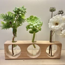 Three small floral stems in glass tubes on a wooden holder