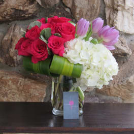 Bouquet of red roses, white hydrangeas, and lavender tulips in a glass vase