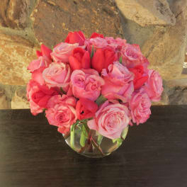 Pink and red roses arranged in a clear glass vase