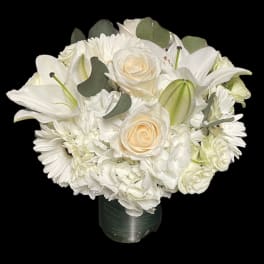 White floral bouquet with roses, lilies, and daisies in a vase