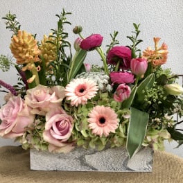 Mixed bouquet with pink roses, gerbera daisies, tulips, and hyacinths in a rectangular vase