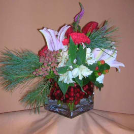 Mixed bouquet with lilies, carnations, and pine in a glass vase