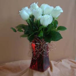 Bouquet of white roses in a red glass vase