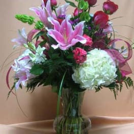 Pink lilies and red roses arranged in a clear glass vase