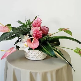 Tropical flower arrangement in a patterned ceramic bowl with pink and white blooms