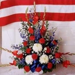 Patriotic red, white, and blue flower arrangement with carnations and mums in a fan shape.